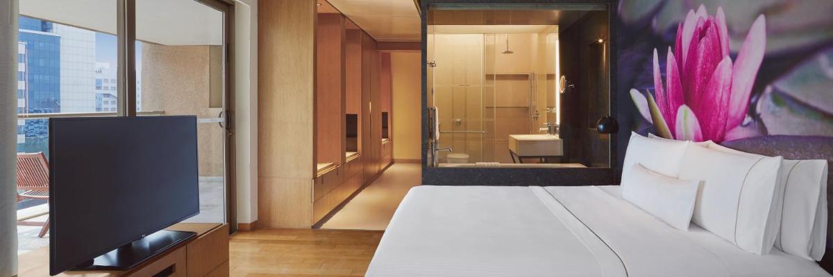 a bedroom with a bed with a television and a bathroom at The Westin Hyderabad Mindspace in Hyderabad