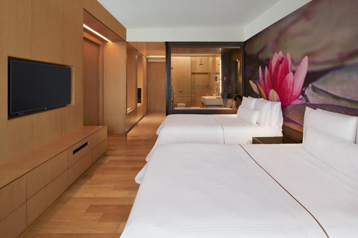 a row of beds in a hotel room with a tv at The Westin Hyderabad Mindspace in Hyderabad