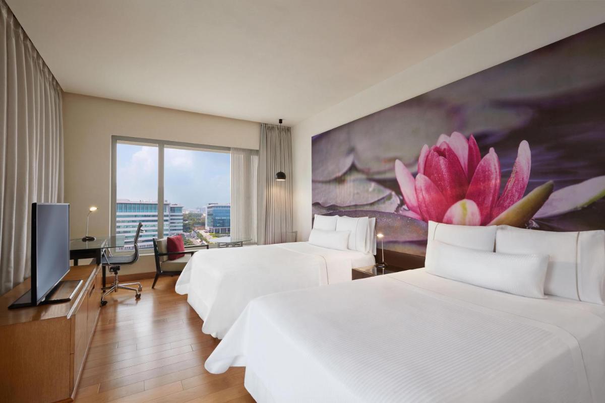 a hotel room with two beds and a large flower on the wall at The Westin Hyderabad Mindspace in Hyderabad