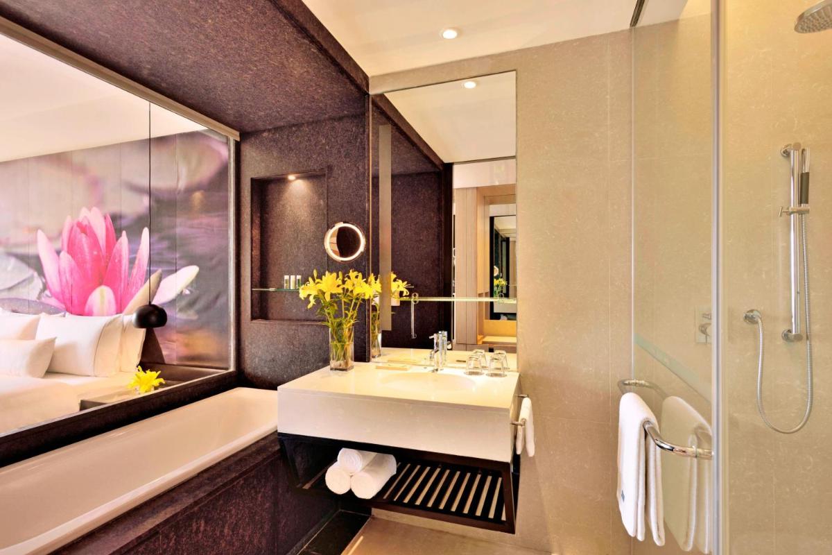 a bathroom with a sink and a bed and a mirror at The Westin Hyderabad Mindspace in Hyderabad