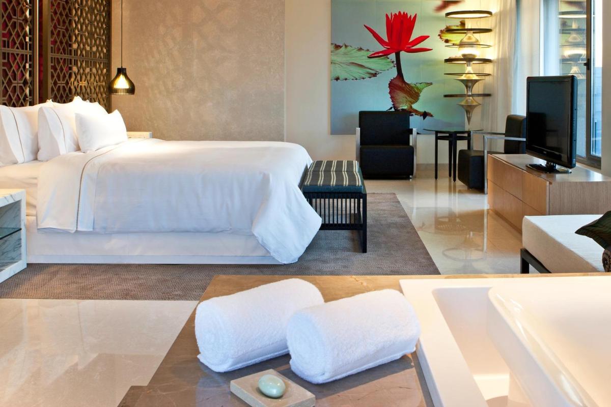 a bedroom with a white bed and a living room at The Westin Hyderabad Mindspace in Hyderabad
