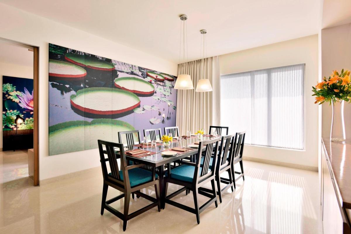 a dining room with a table and chairs and a painting at The Westin Hyderabad Mindspace in Hyderabad