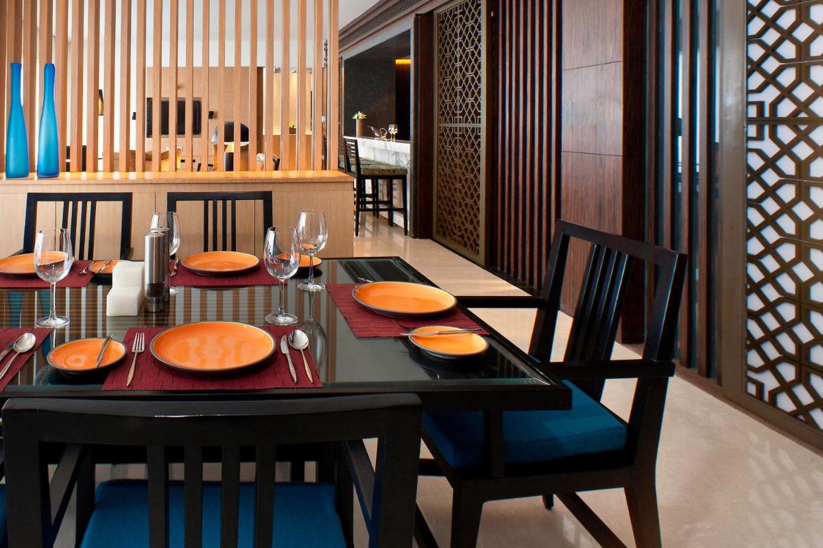 a dining room with a black table with orange plates at The Westin Hyderabad Mindspace in Hyderabad
