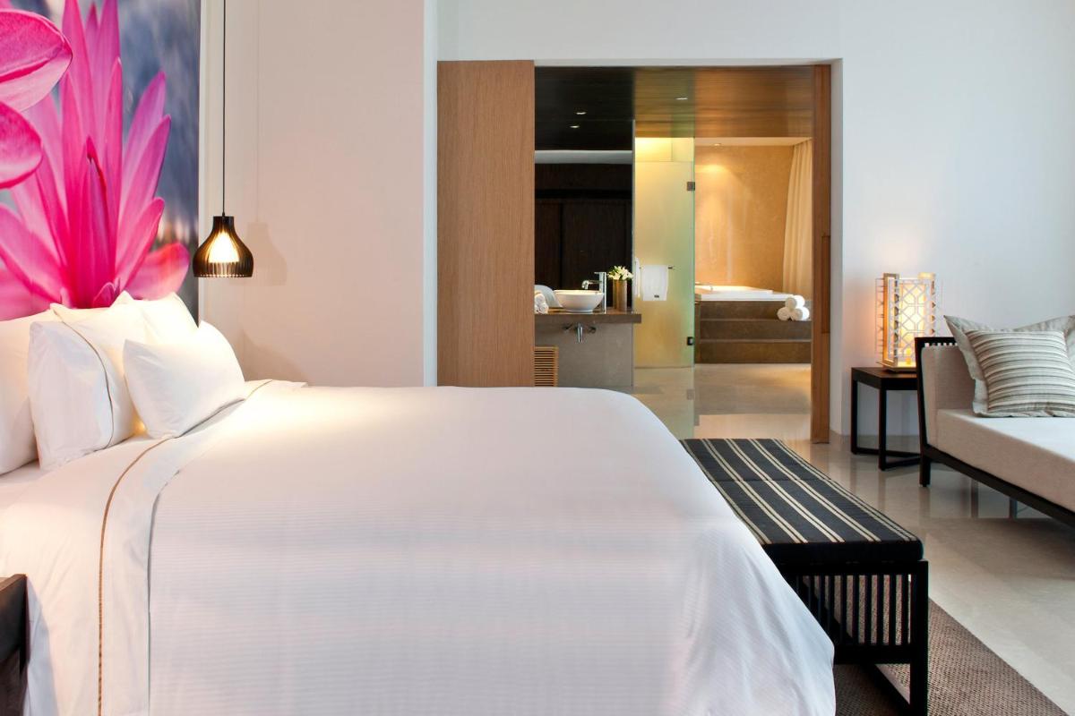a bedroom with a large white bed and a living room at The Westin Hyderabad Mindspace in Hyderabad