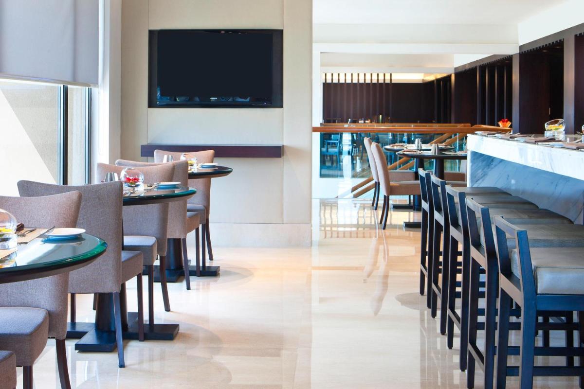 two images of a restaurant with tables and chairs at The Westin Hyderabad Mindspace in Hyderabad