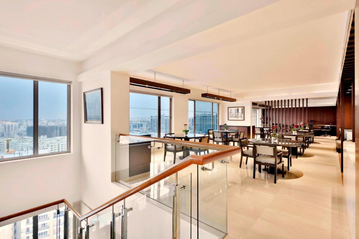 a dining room with tables and chairs and windows at The Westin Hyderabad Mindspace in Hyderabad
