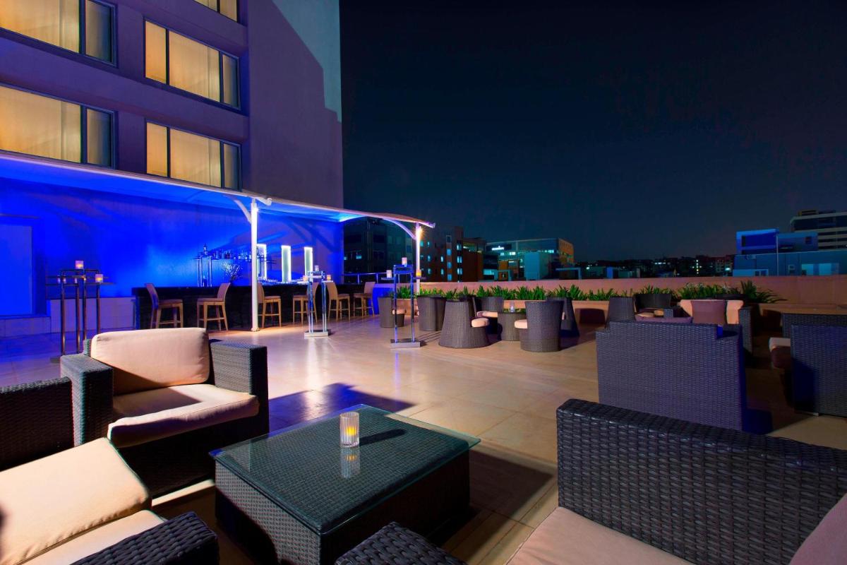 a rooftop patio with couches and tables on a building at The Westin Hyderabad Mindspace in Hyderabad