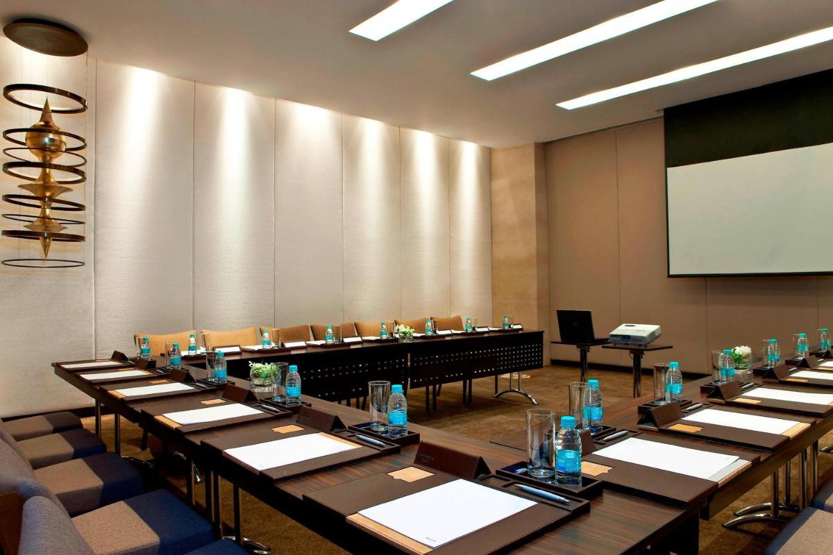 a conference room with long tables and a projection screen at The Westin Hyderabad Mindspace in Hyderabad