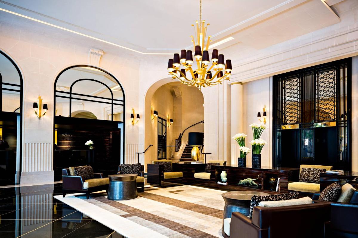 - un hall d'accueil avec un lustre et des chaises dans l'établissement Prince de Galles, un hôtel Luxury Collection, Paris, à Paris