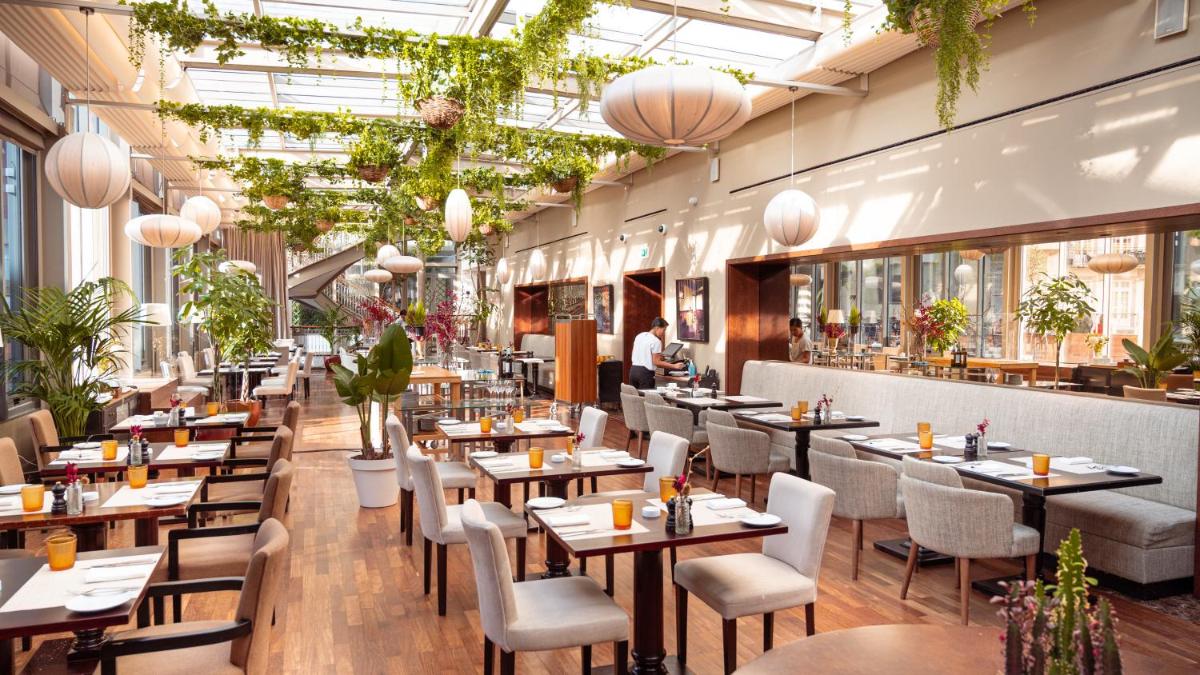 um restaurante com mesas, cadeiras e plantas em InterContinental Porto - Palacio das Cardosas by IHG no Porto