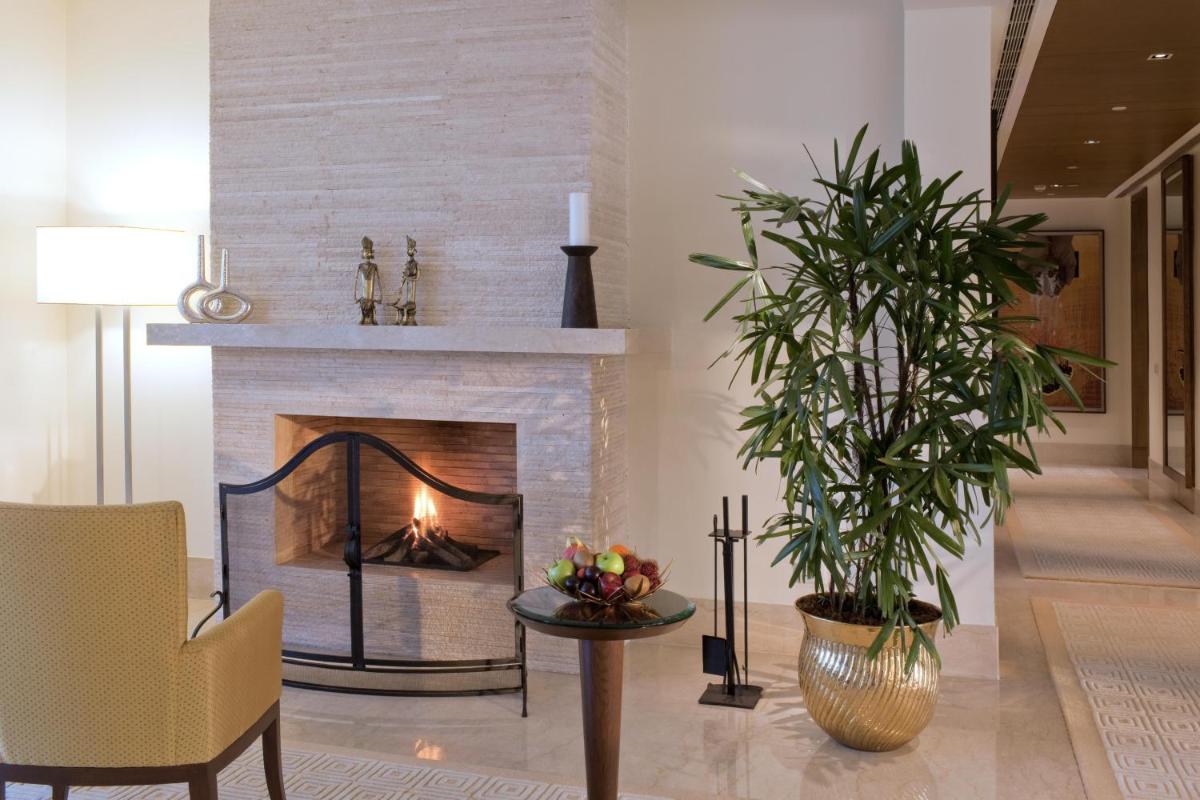 a living room with a fireplace and a chair at The Oberoi Gurgaon in Gurgaon