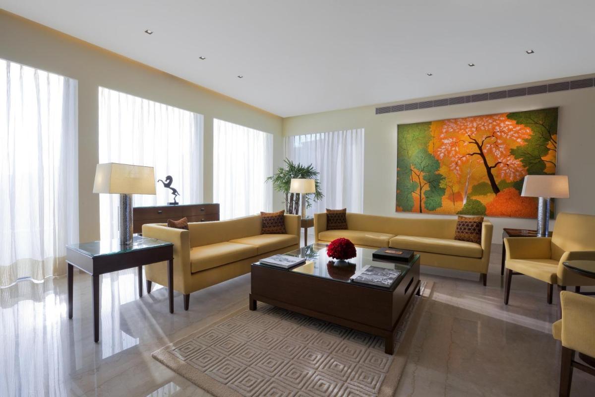a living room with yellow couches and a painting at The Oberoi Gurgaon in Gurgaon