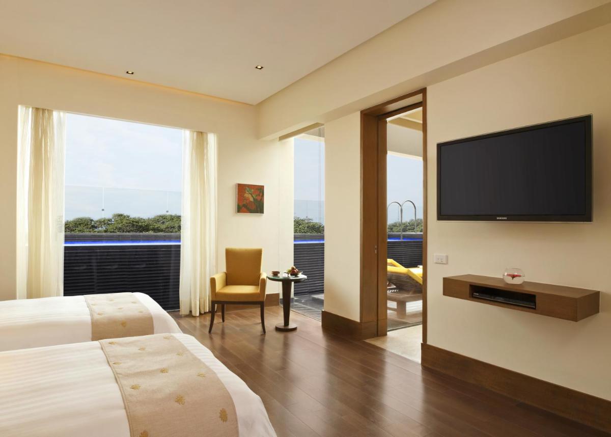 a hotel room with a bed and a flat screen tv at The Oberoi Gurgaon in Gurgaon