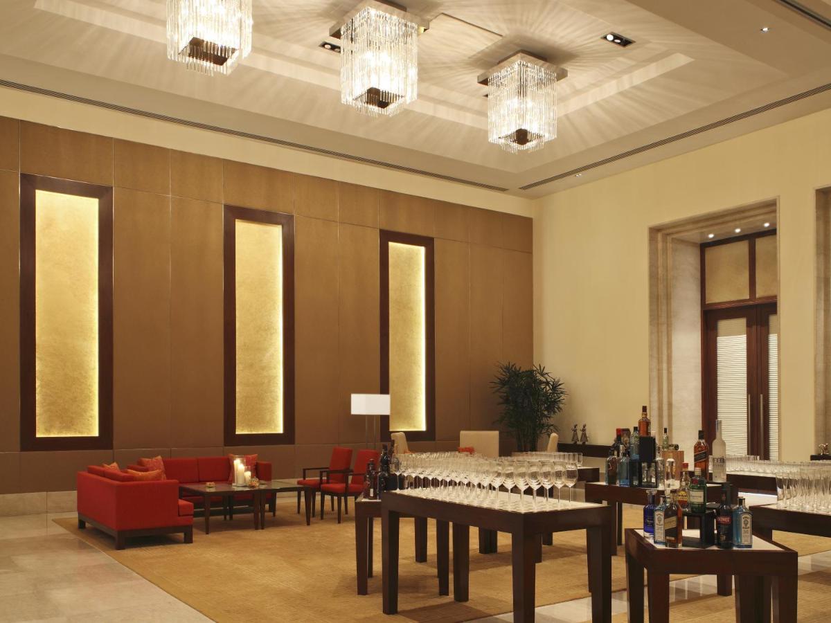 a dining room with tables and chairs and chandeliers at The Oberoi Gurgaon in Gurgaon