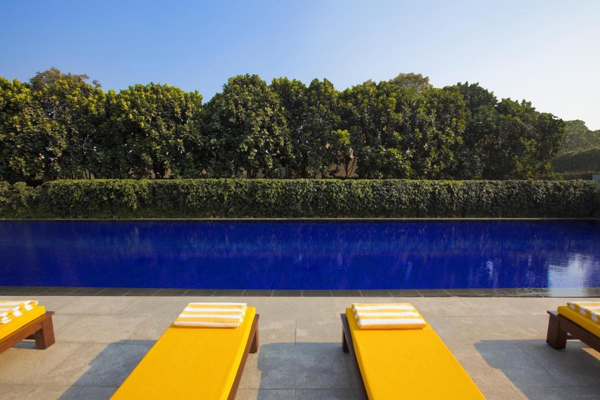 a pool with yellow benches and a blue fence at The Oberoi Gurgaon in Gurgaon