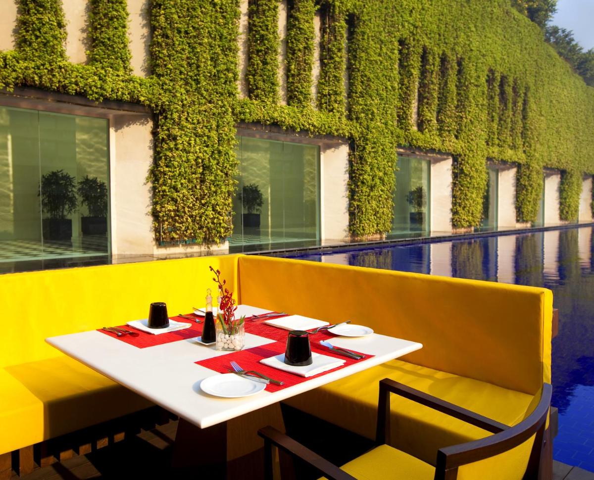 a restaurant with a white table and yellow chairs at The Oberoi Gurgaon in Gurgaon