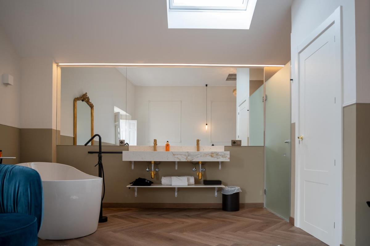 Un baño con bañera y un espejo grande. en Hotel Boutique Las Indianas, en Nueva de Llanes 80 fotos más