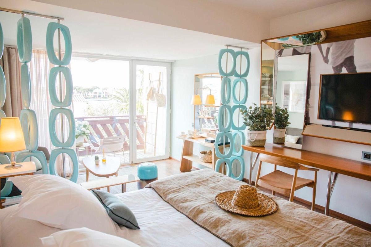 une chambre avec un lit, un bureau et une télévision dans l'établissement Relais et Châteaux Thalasso & Spa Ile de la Lagune, à Saint-Cyprien