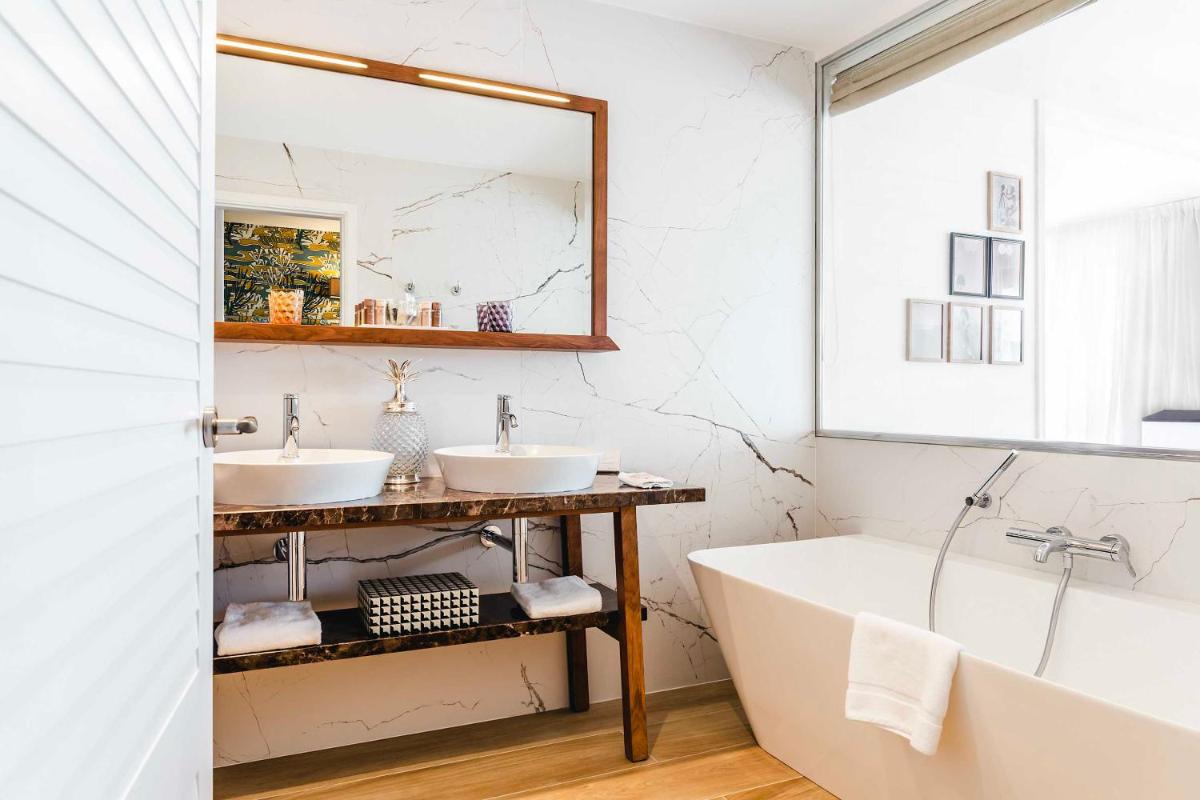une salle de bain avec deux lavabos et une baignoire dans l'établissement Relais et Châteaux Thalasso & Spa Ile de la Lagune, à Saint-Cyprien
