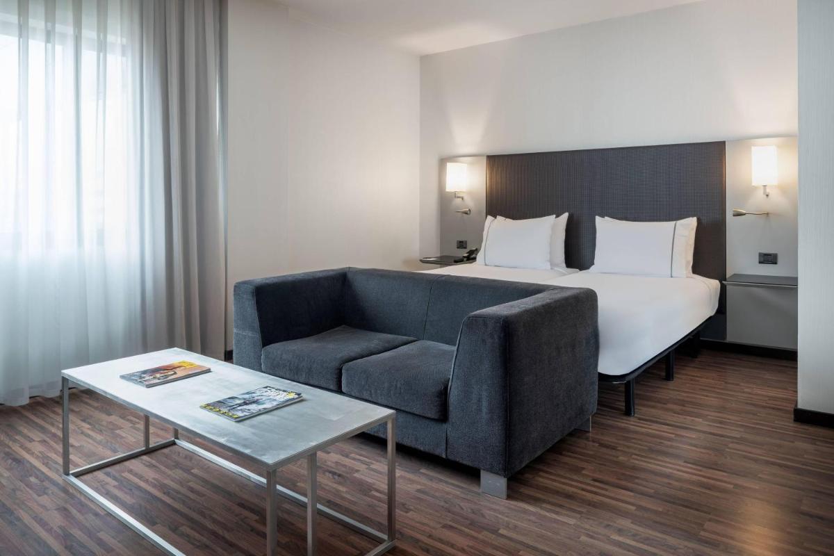 una habitación de hotel con un sofá y una cama en AC Hotel San Sebastián de los Reyes by Marriott, en San Sebastián de los Reyes