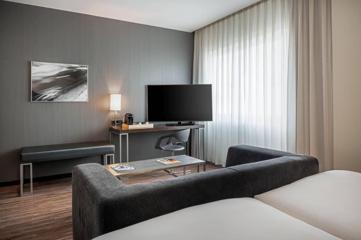 Una habitación de hotel con un sofá y un televisor. en AC Hotel San Sebastián de los Reyes by Marriott, en San Sebastián de los Reyes 32 fotos más