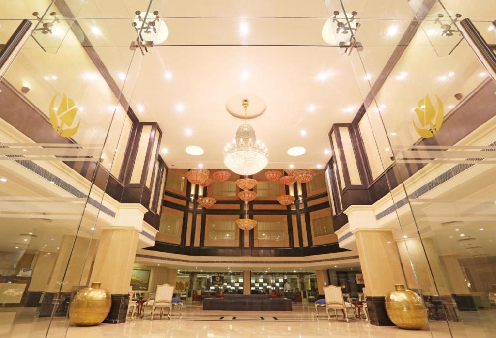 a large lobby with a chandelier and tables and chairs at Golden Tulip Jaipur in Jaipur