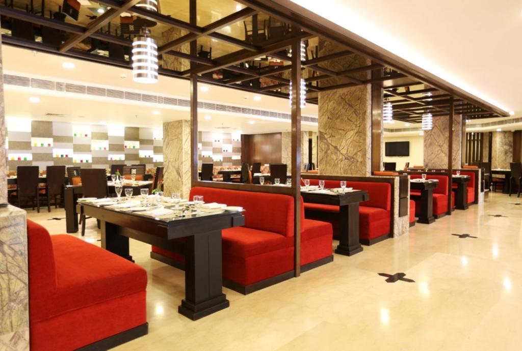 a restaurant with red chairs and tables in a room at Golden Tulip Jaipur in Jaipur
