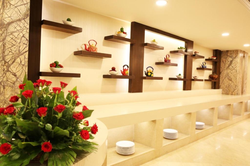 a room with shelves and a vase of red flowers at Golden Tulip Jaipur in Jaipur