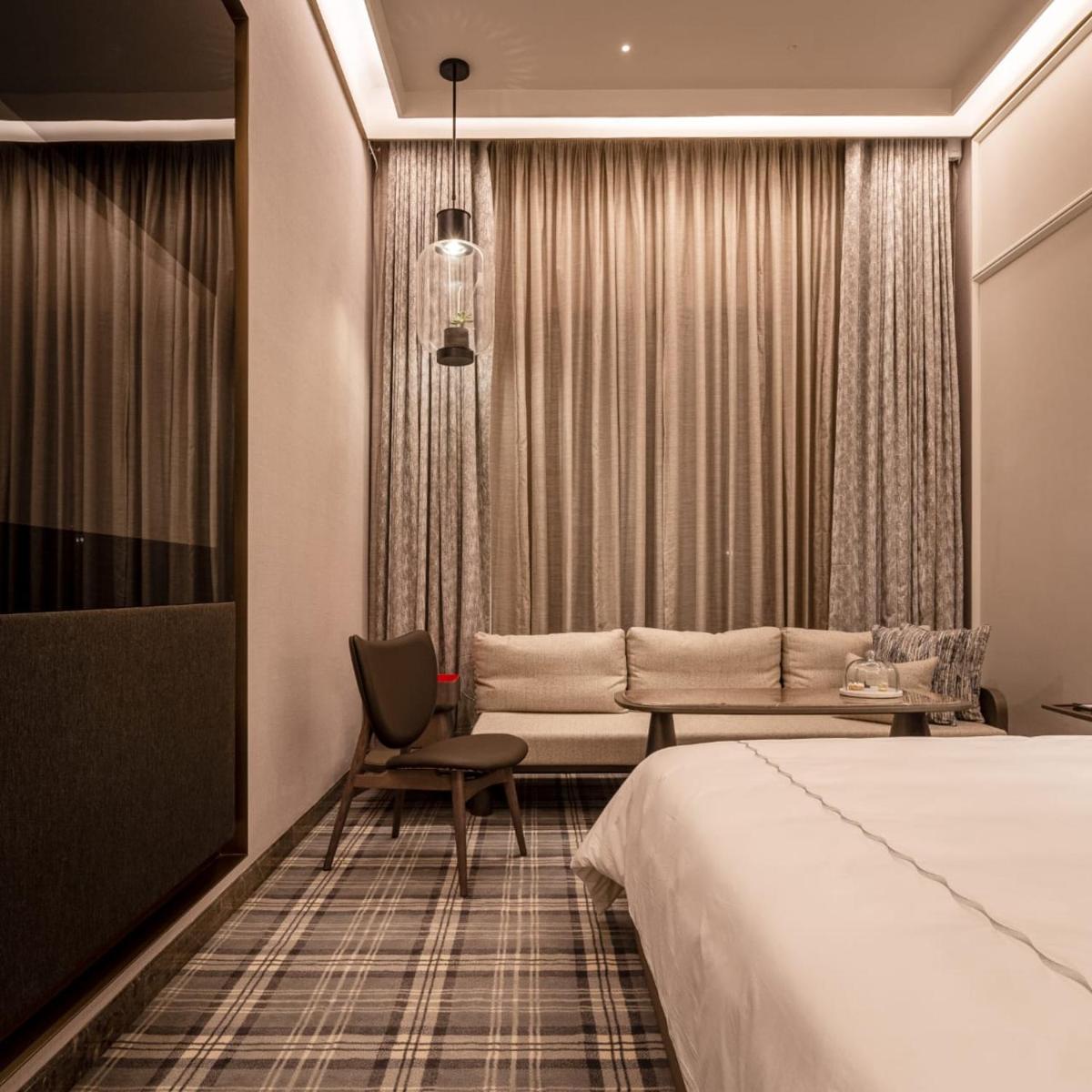 a hotel room with a bed and a chair at The Residency Towers in Chennai