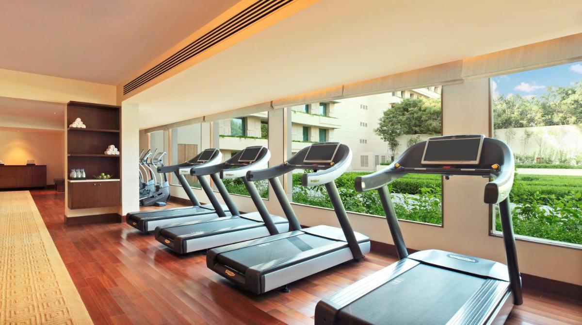 a row of treadmills in a gym with windows at The Oberoi Gurgaon in Gurgaon