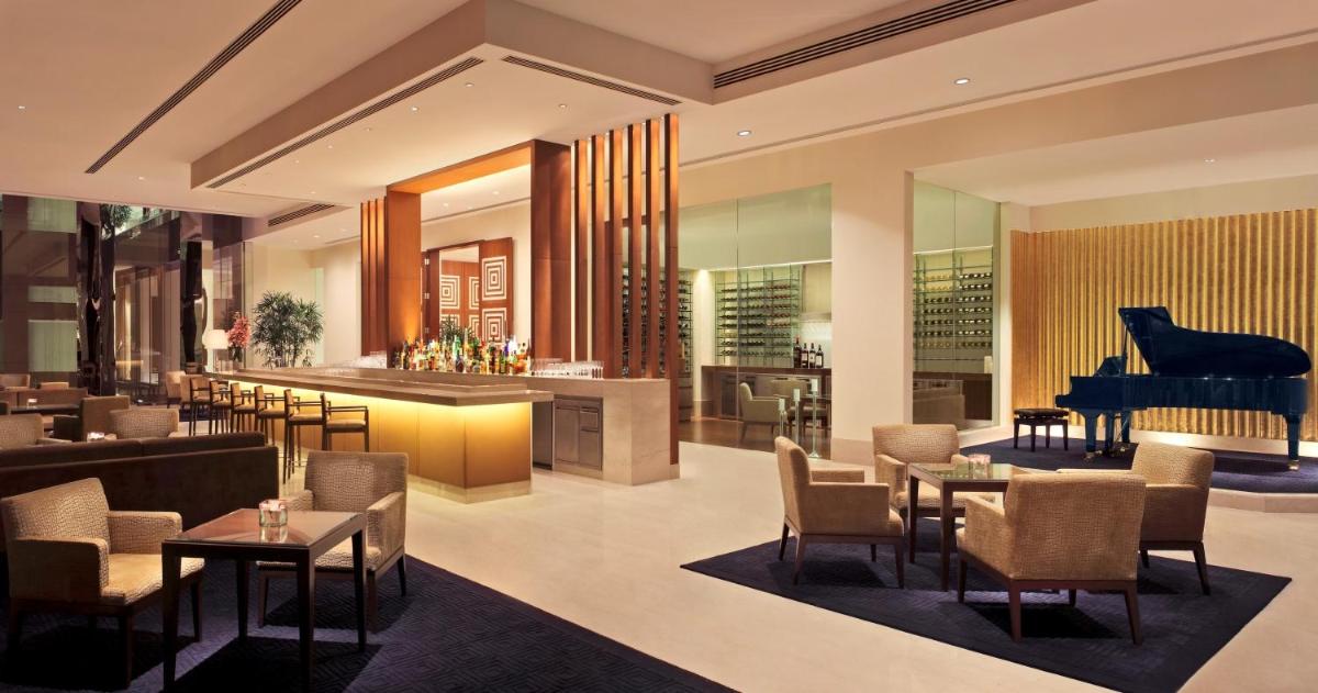 a restaurant with a grand piano in the background at The Oberoi Gurgaon in Gurgaon