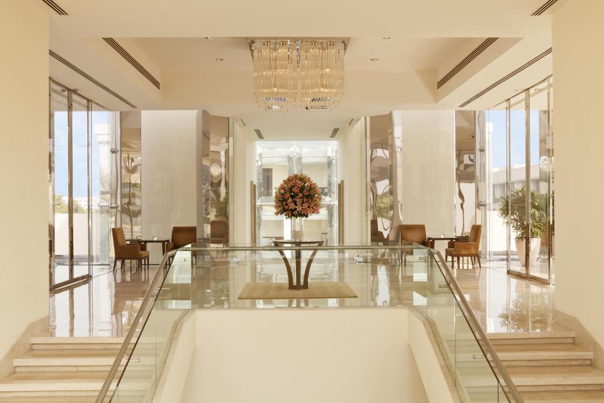 a lobby with a table and chairs and a chandelier at The Oberoi Gurgaon in Gurgaon