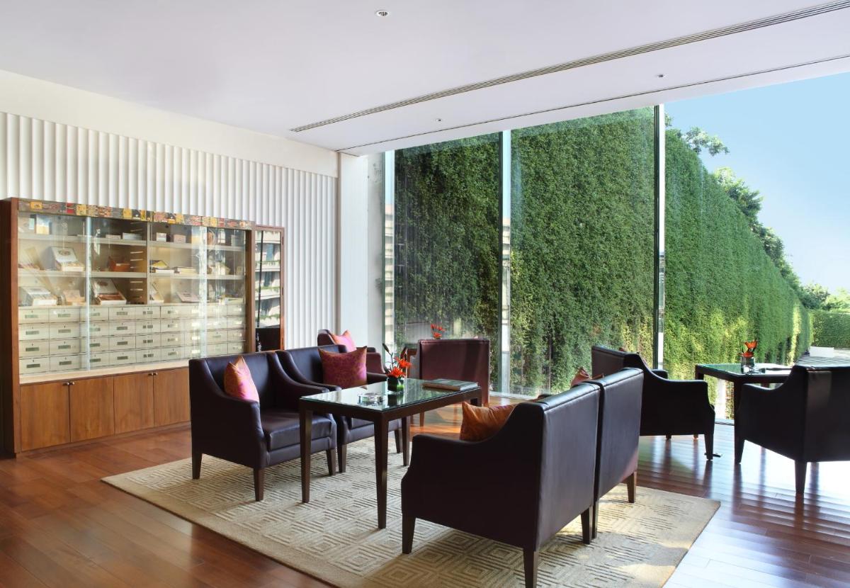 a dining room with tables and chairs and large windows at The Oberoi Gurgaon in Gurgaon