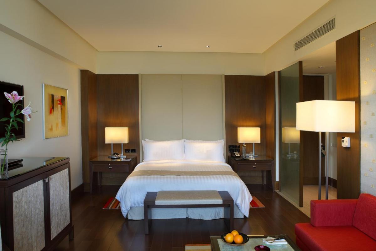 a hotel room with a bed and a red couch at The Oberoi Gurgaon in Gurgaon