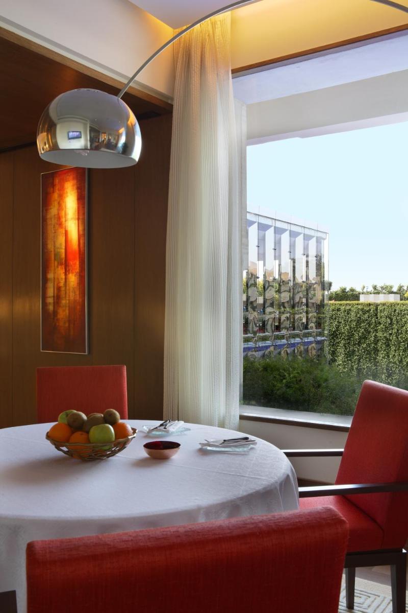 a table with a bowl of fruit and a window at The Oberoi Gurgaon in Gurgaon