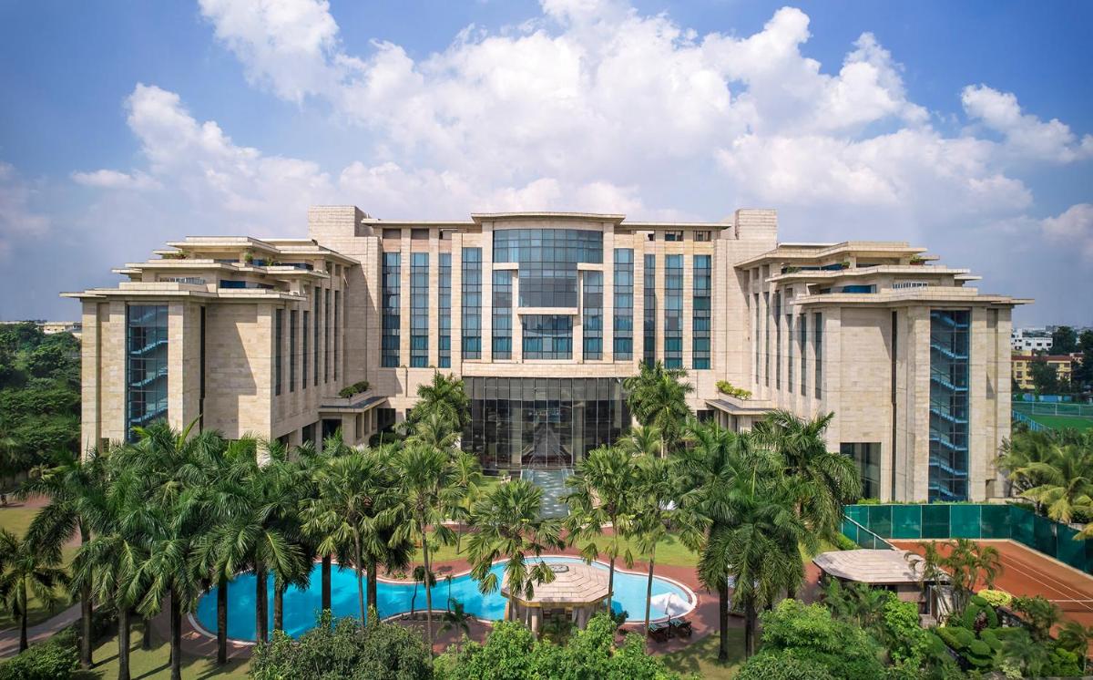 a resort building with a pool and palm trees at Hyatt Regency Kolkata in Kolkata a resort building with a pool and palm trees at Hyatt Regency Kolkata in Kolkata