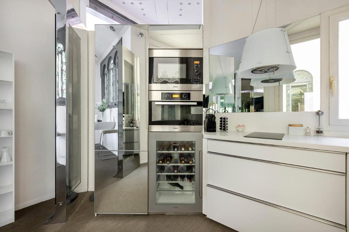 cocina con encimeras blancas y nevera grande de cristal en El Palauet Royal Suites, en Barcelona