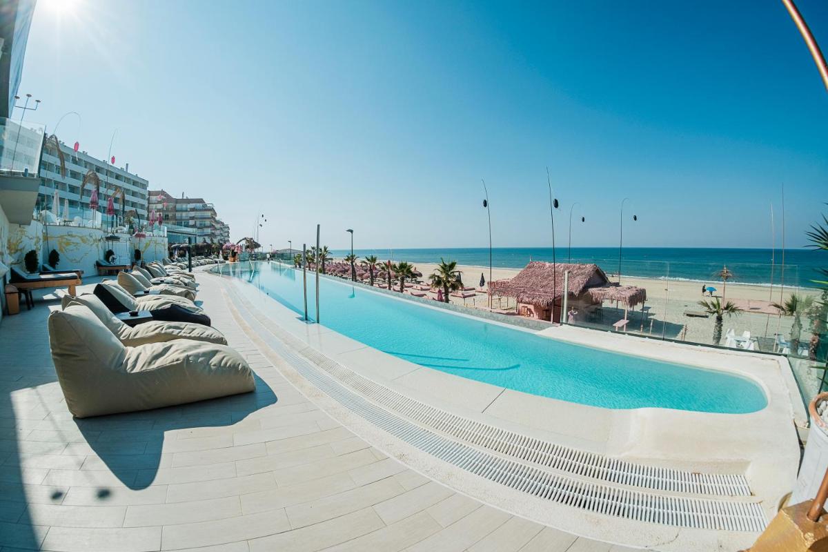 una piscina al lado de un edificio con playa en ON Hotels Oceanfront Adults Designed, en Matalascañas
