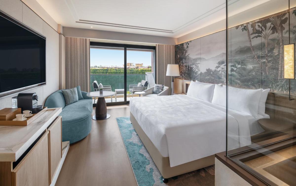 a hotel room with a large bed and a television at JW Marriott Goa in Vagator a hotel room with a large bed and a television at JW Marriott Goa in Vagator