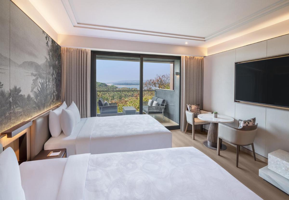 a hotel room with two beds and a flat screen tv at JW Marriott Goa in Vagator +123 photos a hotel room with two beds and a flat screen tv at JW Marriott Goa in Vagator +123 photos