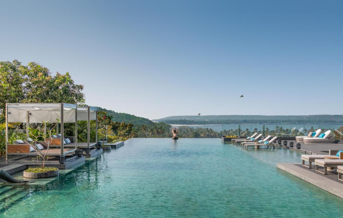 a swimming pool with lounge chairs in the water at JW Marriott Goa in Vagator a swimming pool with lounge chairs in the water at JW Marriott Goa in Vagator