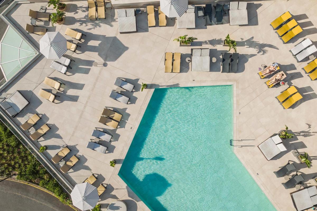 Vista aérea de uma piscina com espreguiçadeiras. em The Views Baia - Adults Only no Funchal