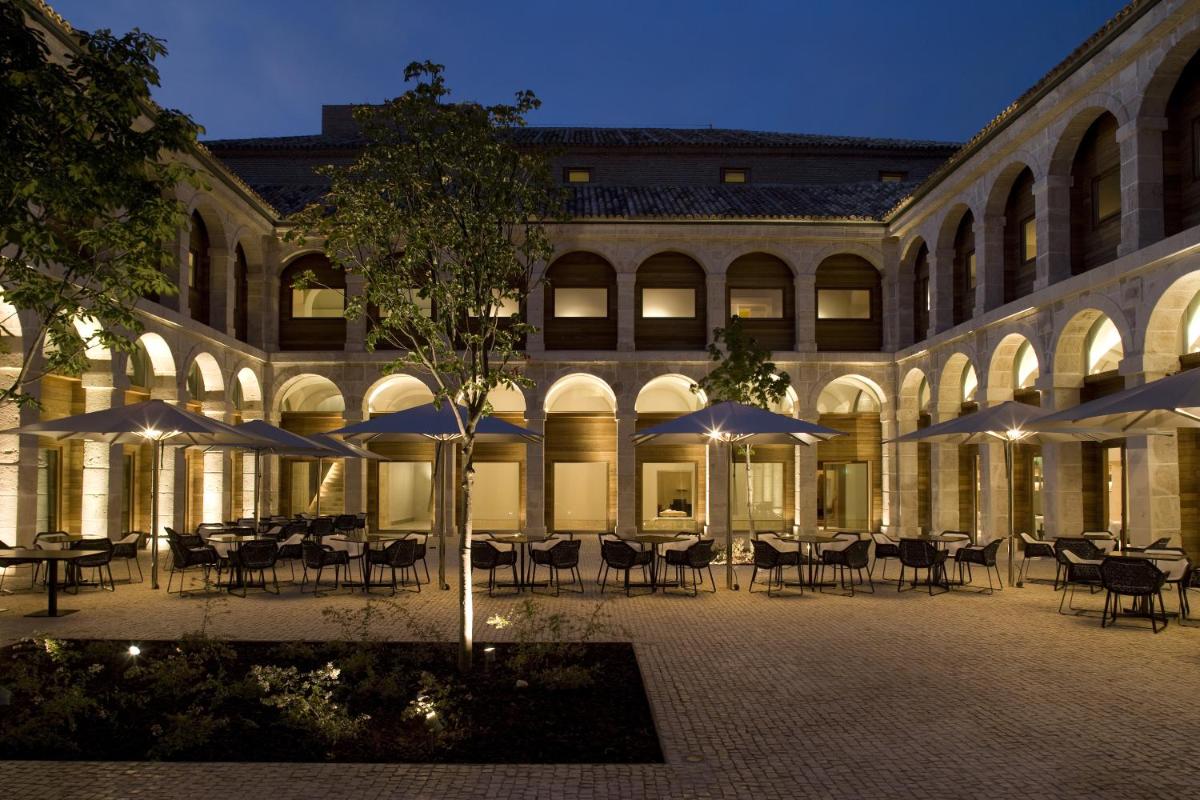 un edificio con mesas y sombrillas en un patio en Parador de Alcalá de Henares, en Alcalá de Henares
