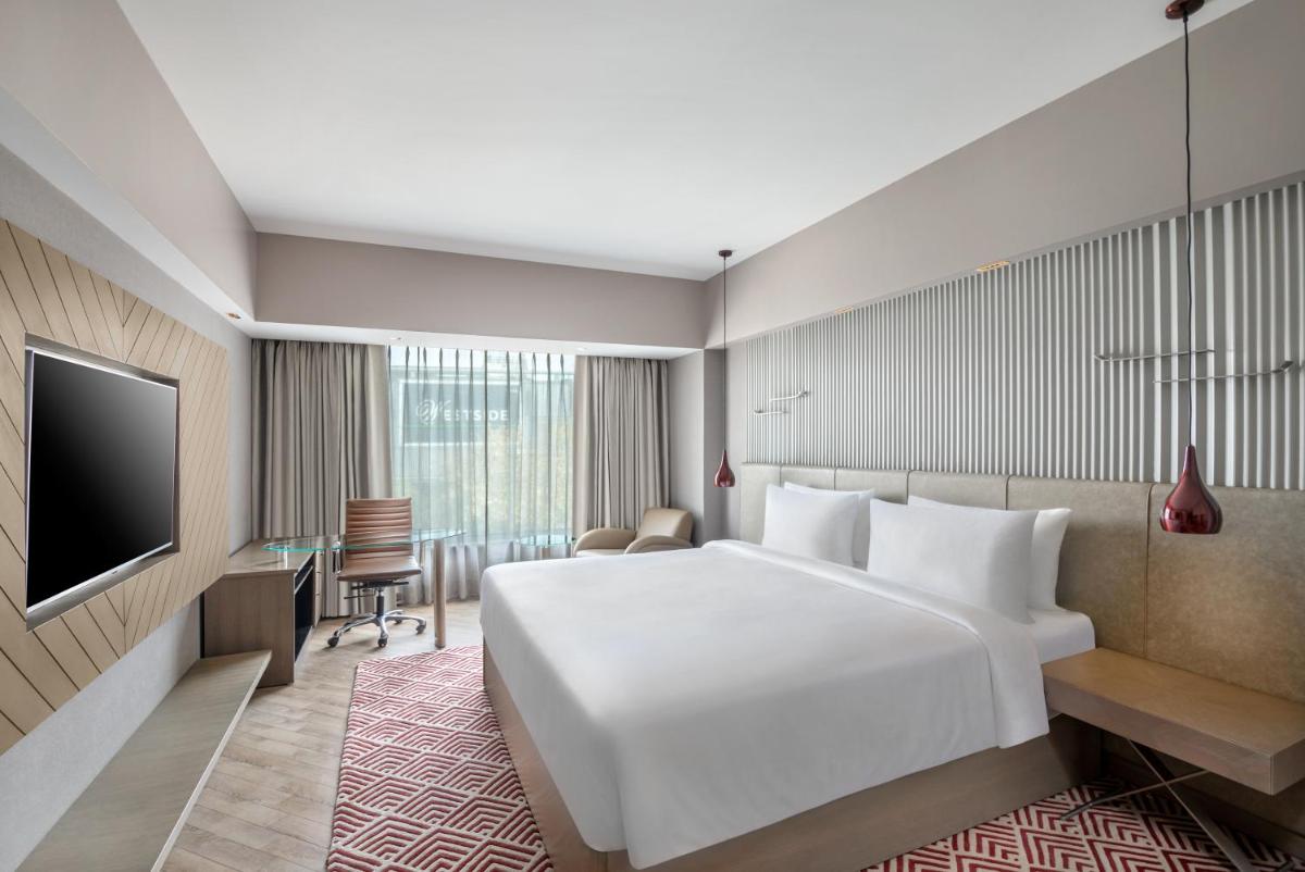 a hotel room with a large white bed and a desk at Radisson Hotel Sector 29 Gurugram in Gurgaon
