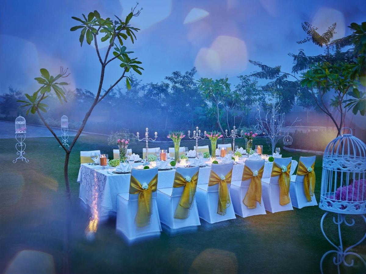 a table with yellow and white chairs and a bird cage at Vivanta New Delhi, Dwarka in New Delhi a table with yellow and white chairs and a bird cage at Vivanta New Delhi, Dwarka in New Delhi