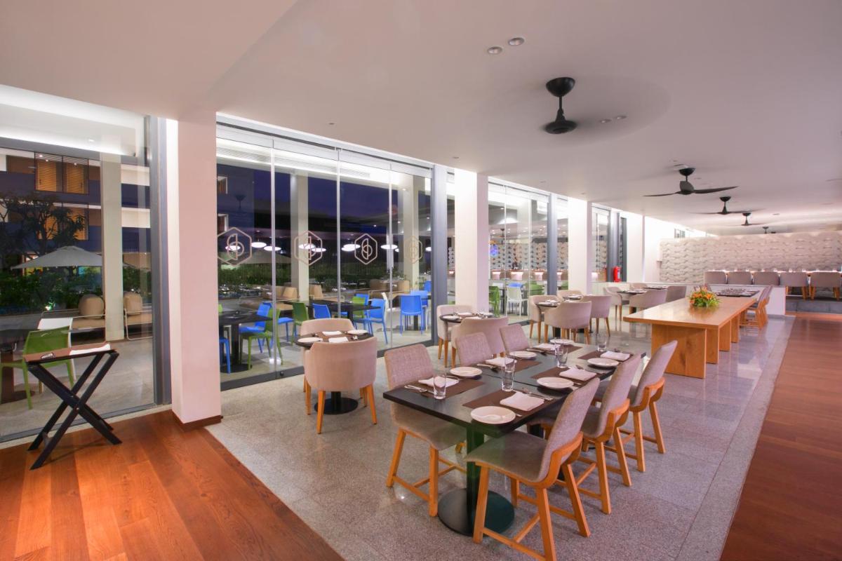 a dining room with tables and chairs and windows at BLVD Club - Near BENGALURU AIRPORT in Bengaluru