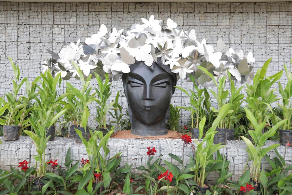 a statue with white flowers in a garden at BLVD Club - Near BENGALURU AIRPORT in Bengaluru