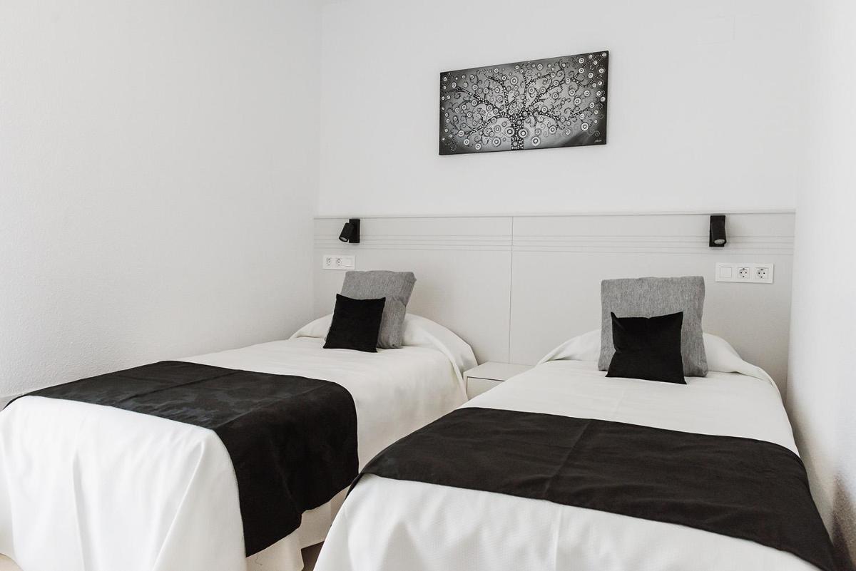 Dos camas en una habitación con paredes blancas. en Nacavi Albir Aparthotel, en Albir 43 fotos más