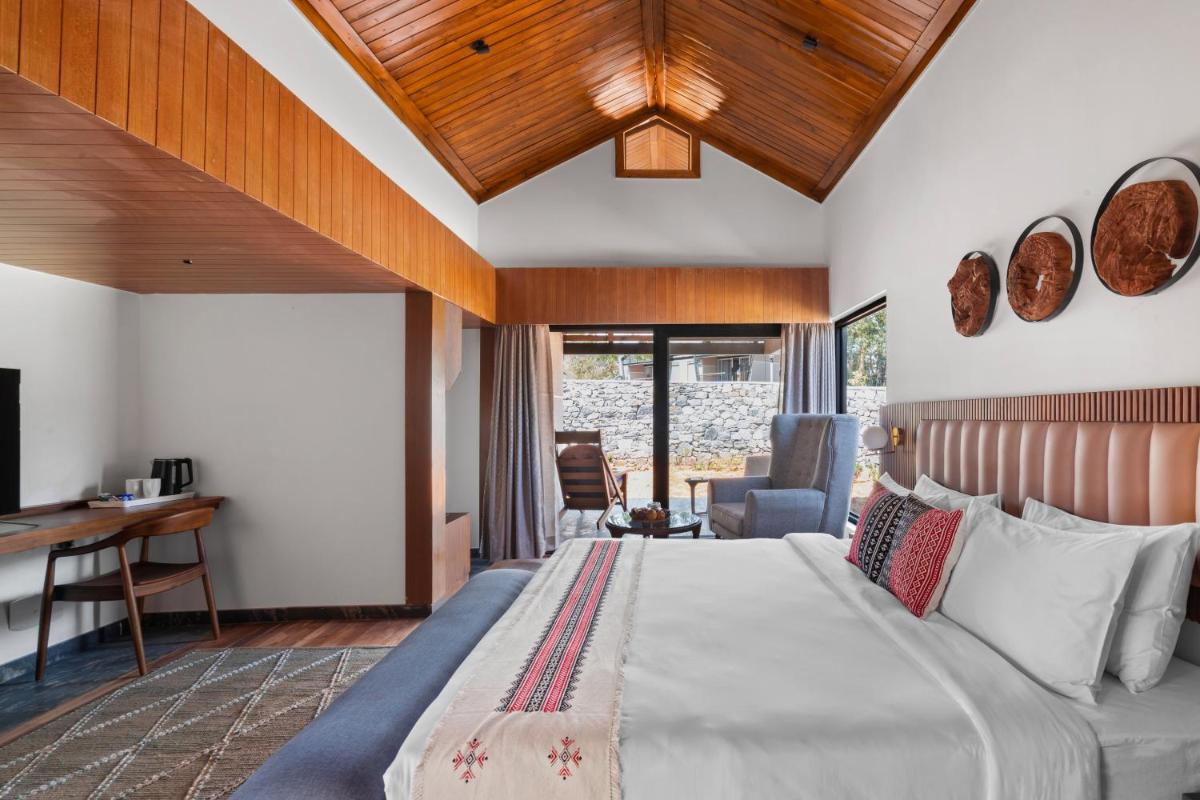 a bedroom with a bed and a desk in a room at WelcomHeritage Ayatana Ooty in Ooty +57 photos