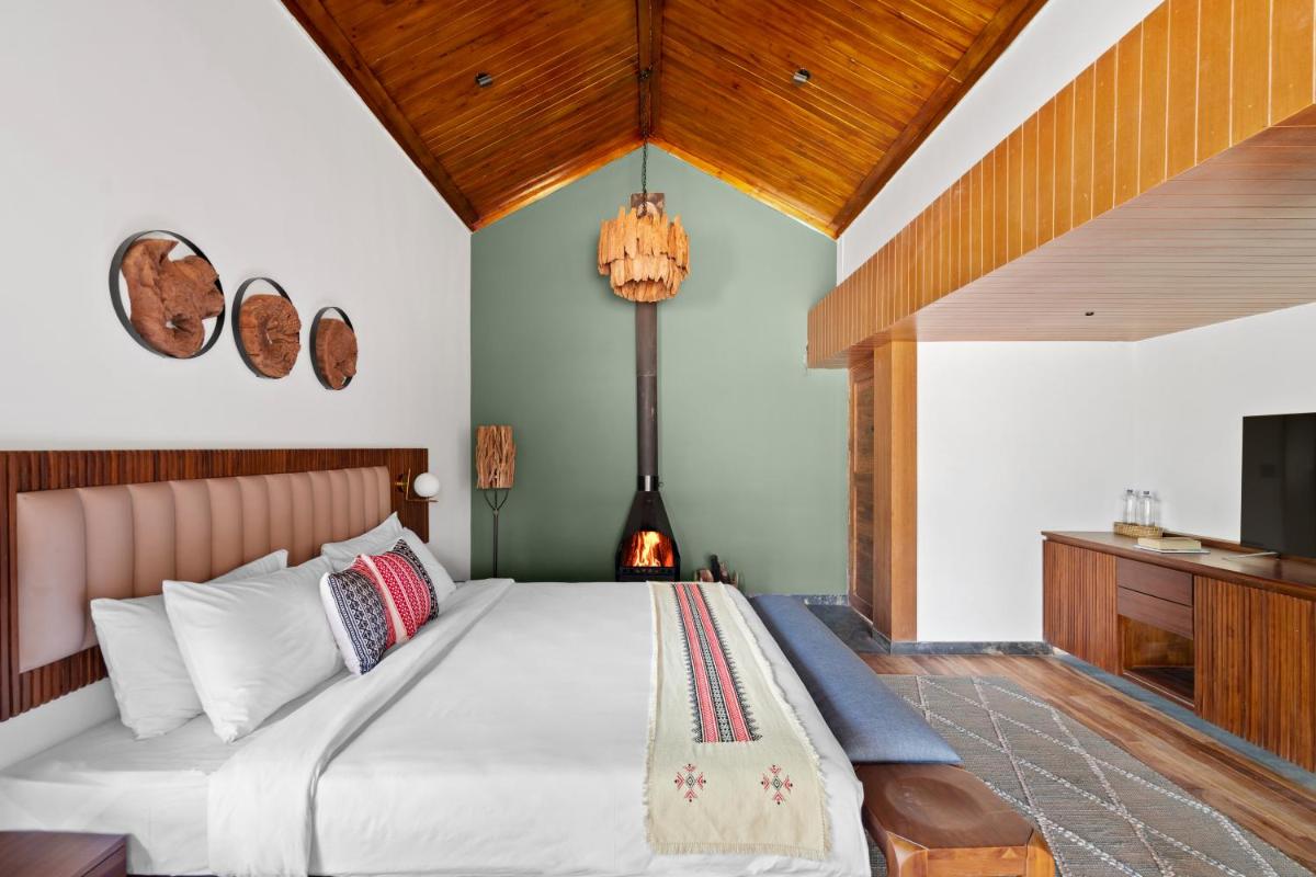 a bedroom with a large bed and a fireplace at WelcomHeritage Ayatana Ooty in Ooty